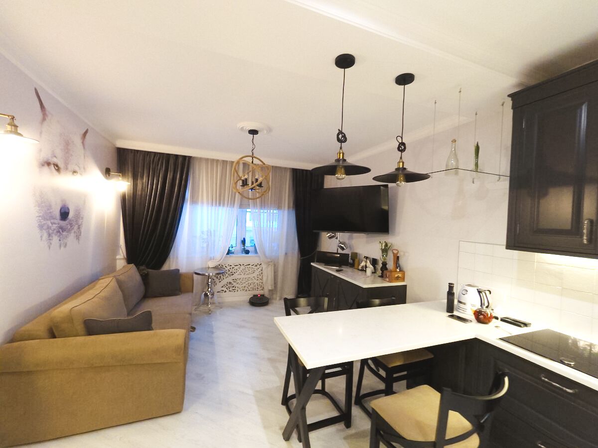 эклектика на кухне: строгие формы гарнитура, современный мягкий диван и бархатные шторы