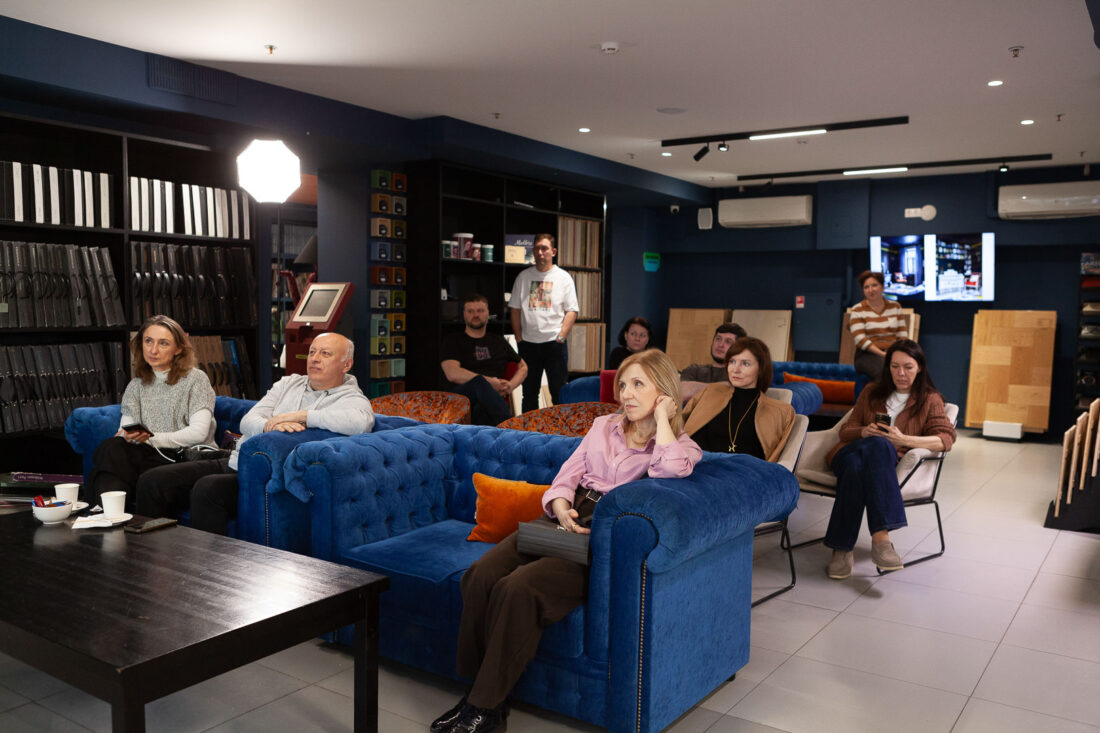 Зал дизайн‑центра Ампир Декор на Автозаводской во время лекции: участники клуба сидят на ярко‑синих и оранжевых диванах среди стеллажей с образцами материалов
