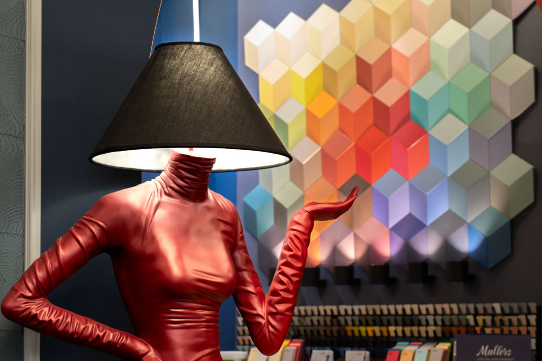 Инсталляция с красным напольным светильником‑фигурой на фоне объёмной цветовой палитры красок Mallers в дизайн‑центре Ампир Декор на Автозаводской