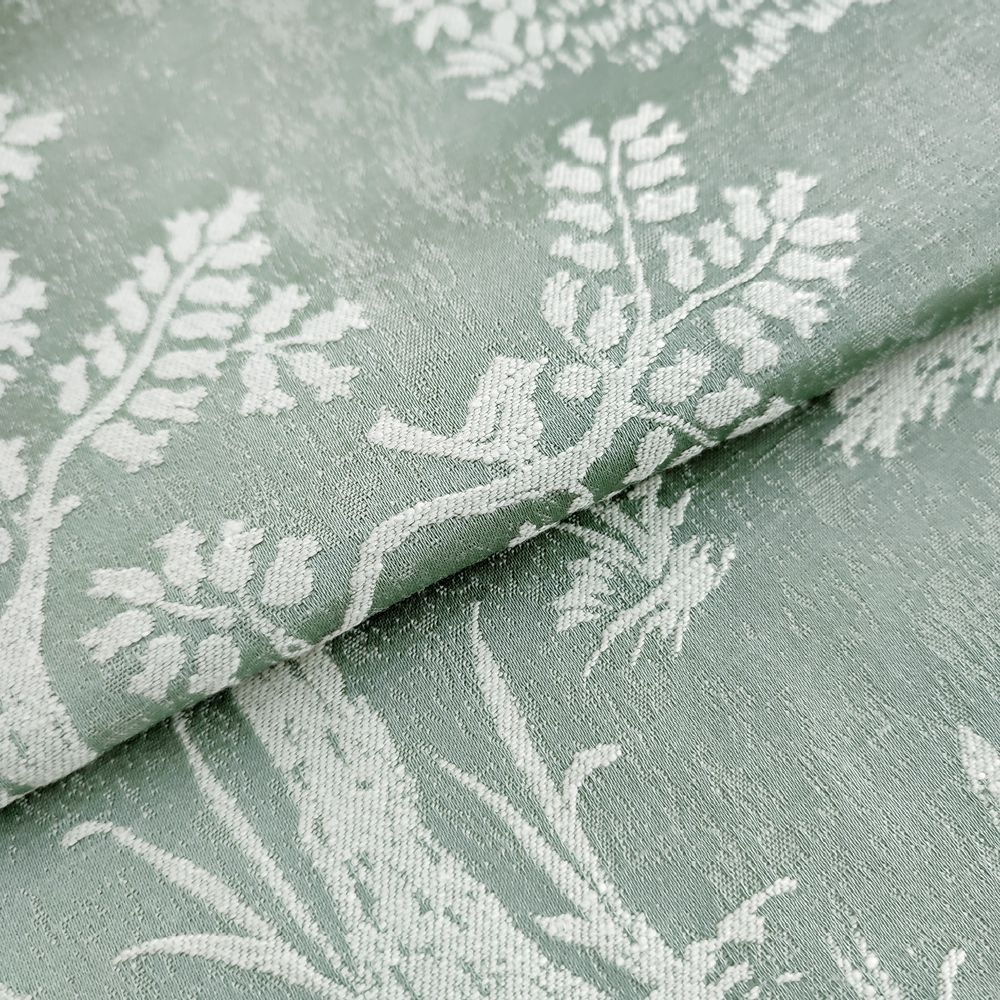 Крупный план оливково-зелёной жаккардовой ткани с матово‑глянцевой фактурой и светлым анималистическим рисунком веток, птиц, ежиков, оленей и растительности, сложенной мягкими слоями.