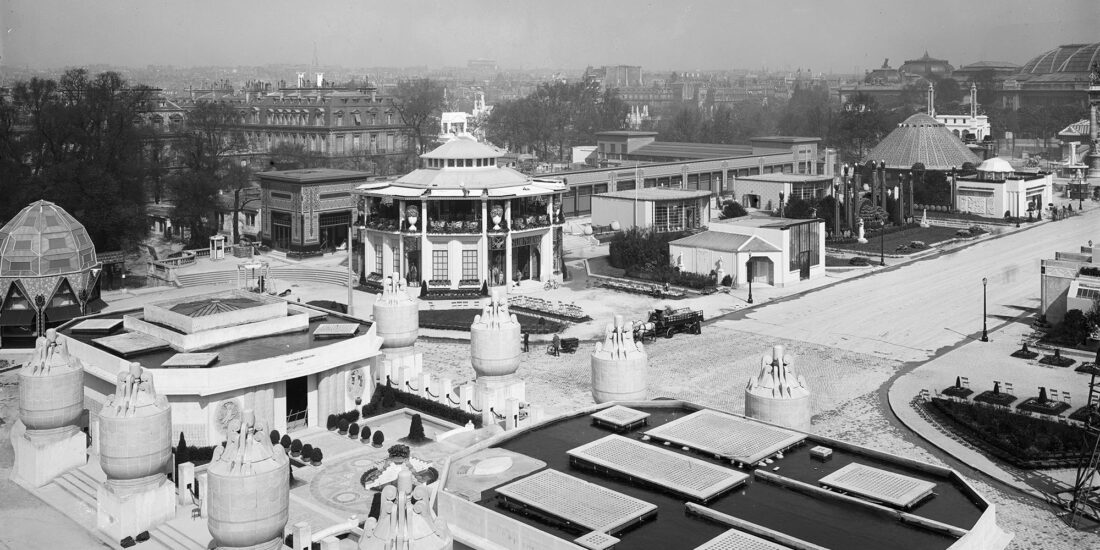 Панорамный чёрно-белый вид павильонов Международной выставки декоративного и промышленного искусства в Париже 1925 года с геометрическими зданиями и фонтанами в стиле ар-деко.